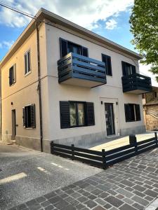 ein weißes Gebäude mit schwarzen Fensterläden an einer Straße in der Unterkunft SottoStelle in Santa Maria degli Angeli