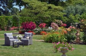 a garden with two chairs and a table and flowers at Hostellerie de la Motte jean in Saint-Coulomb