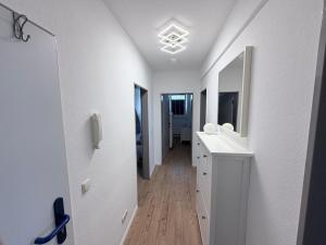 a hallway of a bathroom with white walls and wooden floors at Gemütliche Ferienwohung in Neubrandenburg +4 photos