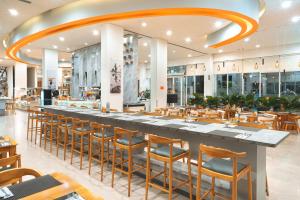 a restaurant with a long bar with wooden chairs at HARRIS Hotel Batam Center in Batam Center