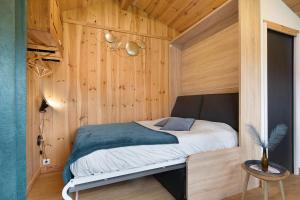 a small bedroom with a bed in a wooden wall at Ma cabane Océan in Le Verdon-sur-Mer