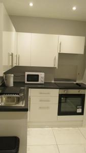 a kitchen with white cabinets and a microwave at Rooms at The Ritz Complex in Desborough