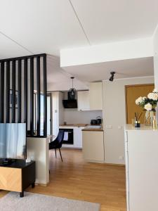 a kitchen and living room with white cabinets and a tv at River Apartment in Pärnu +12 photos