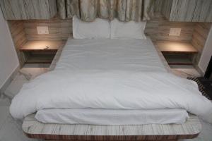 a bed with white sheets and pillows on it at Palash Baag in Jodhpur