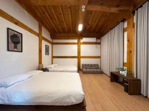 a bedroom with two beds and a wooden ceiling at Luxury Hanok Blue Serenity in T'ongjin