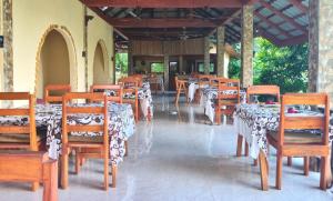 a dining room with tables and chairs with white table cloth at Tangkoko Sanctuary Villa in Bitung