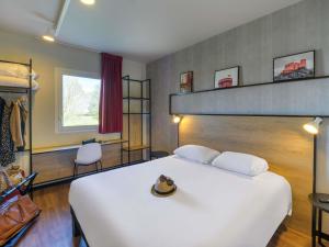 a bedroom with a white bed with a hat on it at ibis Falaise Coeur de Normandie in Falaise +136 photos