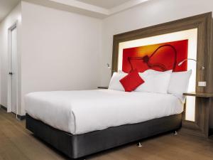 ein Schlafzimmer mit einem großen weißen Bett und roten Kissen in der Unterkunft Novotel Darwin CBD in Darwin