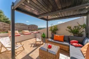 a patio with a couch and chairs under a pergola at Mon Cabanon Roquemaure in Roquemaure