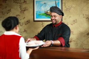 a man is handing a plate of cake to a woman at Hills & Cruise Luxury Houseboats in Alleppey