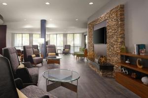 a lobby with a waiting room with chairs and a tv at Courtyard by Marriott Valdosta in Valdosta