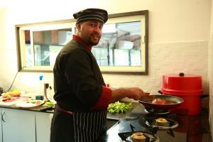 a man in a kitchen preparing food in a wok at Hills & Cruise Luxury Houseboats in Alleppey