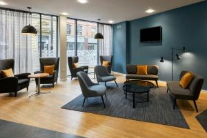 a waiting room with chairs and tables and a tv at Four Points Flex by Sheraton Newcastle in Newcastle upon Tyne