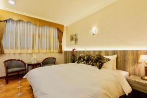 a bedroom with a white bed and a table and chairs at Kending Kaying Hotel in Hengchun South Gate