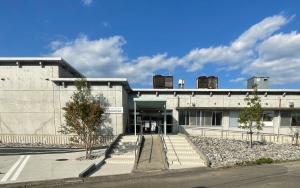 a large concrete building with a door and trees in front at cocomio in Bungoono