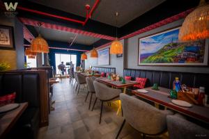 a restaurant with long tables and chairs and a painting on the wall at Weekend Retreat- Hotel & Spa in Kurseong