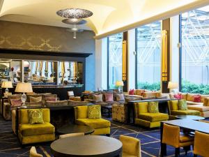 a lobby with yellow chairs and tables and windows at Sofitel Melbourne On Collins in Melbourne