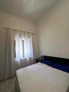 a bedroom with a white bed and a window at Vico Poerio 1 in Tursi