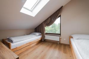 a attic bedroom with two beds and a window at TATRYSTAY Happy Nest Apartments in Tatranská Lomnica