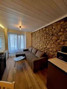 ein Wohnzimmer mit einer Couch und einer Steinwand in der Unterkunft Rustic ABAT 18 in Puigcerdà