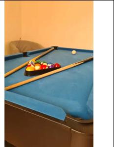 a pool table with two cuesticks on top of it at Grand gîte 150 m2 - 4 chambres - Salle de jeux avec billard et fléchettes in Péronne