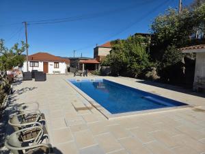 a swimming pool with chairs next to a house at RECANTO da VONINHA in Castelo de Paiva