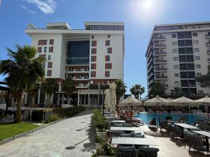 a hotel with tables and umbrellas next to a pool at Niko Apartaments Shengjin in Shëngjin