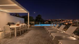 a patio with chairs and a table and a pool at Villa Goa - By Luxury Villas Malta in Mellieħa