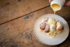 a person pouring syrup onto two pastries on a plate at Lahnerhof Chalets - Mountain view and Sauna inclusive in Lutago