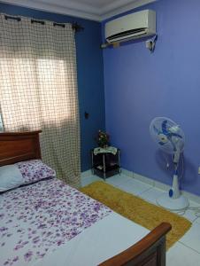 a bedroom with a bed and a fan at Palace Ndogbong Bifaga in Bassa