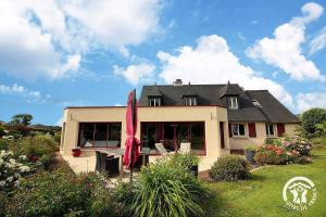 ein Haus mit Terrasse und einem roten Sonnenschirm in der Unterkunft La suite orchidée in Paimpol
