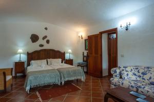 een slaapkamer met een bed en een bank bij Casa-Cueva El Pastor in Artenara