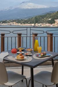 a table with plates of food on a balcony at UNA Hotels Capotaormina in Taormina
