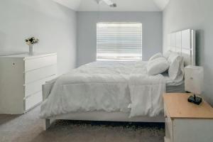 a white bedroom with a large bed and a window at Nyakio Suite in Chesapeake