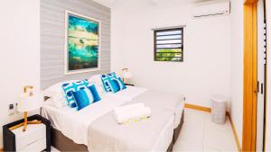 a white bedroom with two beds and a window at Latitude By Horizon Holidays in Rivière Noire +18 photos