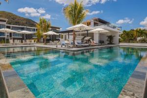 a swimming pool with blue water in front of a building at Latitude By Horizon Holidays in Rivière Noire