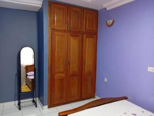 a bedroom with a wooden cabinet and a mirror at Palace Ndogbong Bifaga in Bassa +7 photos