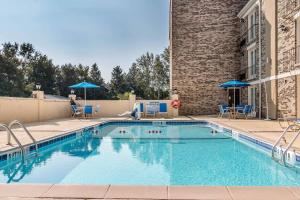 a swimming pool with chairs and umbrellas next to a building at Comfort Inn Savannah Midtown in Savannah