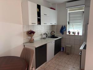 a small kitchen with white cabinets and a table at Apartman Ana in Trebinje