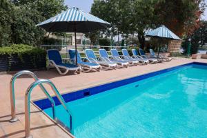 a swimming pool with lounge chairs and umbrellas next to a pool at Beach Luxury Hotel in Karachi