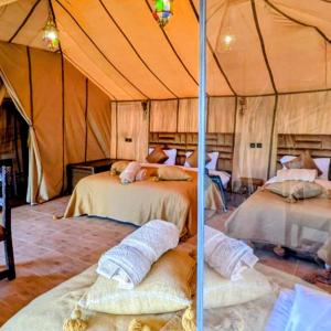 a bedroom with two beds in a tent at Sunset Dunes Luxury Camp in Merzouga +29 photos