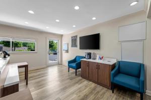 a room with two blue chairs and a desk and a tv at Suburban Studios Charlotte - Ballantyne in Charlotte