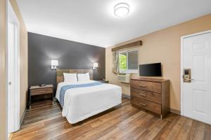 a bedroom with a white bed and a television at Suburban Studios Charlotte - Ballantyne in Charlotte
