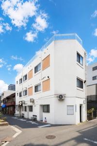 a white building on the side of a street at Namba 5min by subway OYASUMI Manga HOTEL 24 hours Self-check-in Japanese-Style hotel in Osaka