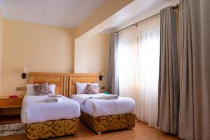 a bedroom with two beds and a window at Nyeri Club in Nyeri +33 photos