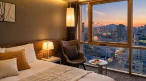 a hotel room with a bed and a chair and a window at Staz Hotel Ulsan in Ulsan +69 photos