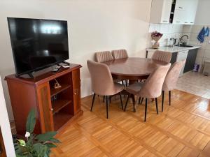a dining room table with chairs and a flat screen tv at Apartman Ana in Trebinje +6 photos