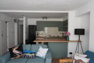 a living room with a blue couch and a kitchen at Garden flat seafront Hastings in Hastings