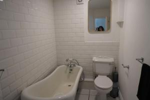 a bathroom with a tub and a toilet and a mirror at Garden flat seafront Hastings in Hastings