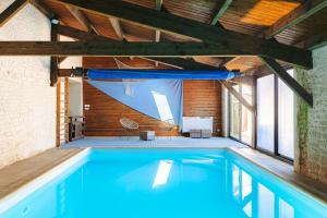 a swimming pool in a building with a wooden ceiling at Mimosa in La Jarrie +25 photos